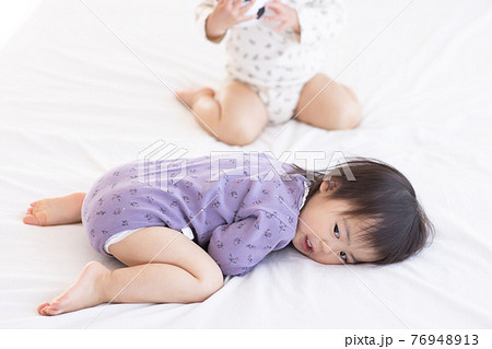 ベッドに寝転ぶ幼児 76948913