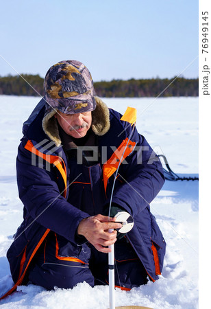 ice fishing. fisherman fishing on frozen lake. Winter frosty morning fishing on river. Vertical photo 76949145