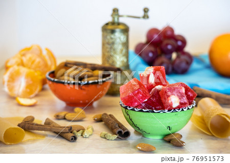 Turkish delight or lokum in a green bowl with grapes, mandarines, nuts, spices - a great arabic dessert. 76951573