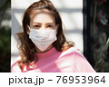 フェースマスクを付けて外で立っている若い女性 76953964