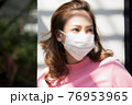 フェースマスクを付けて外で立っている若い女性 76953965