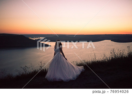 Silhouette of bride in a wedding dress at night against lake and islands 76954026