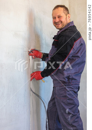An electrician is laying a cable in an electrical wiring ditch 76954142