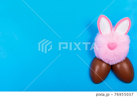 Easter, chocolate egg, pink toy rabbit head on a blue background. Easter, chocolate egg, pink toy rabbit head on a blue background. 76955037