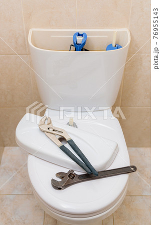 Plumbing tools in the toilet on a white toilet bowl 76955143