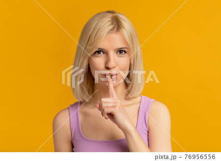 Keep silence. Mysterious woman showing shhh sign at camera, holding finger near lips, posing over yellow background 76956556