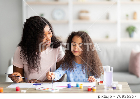 Portrait of happy black mother and her daughter painting with watercolors and gouache at home. Family hobbies concept Portrait of happy black mother and her daughter painting with watercolors and gouache at home. Family hobbies concept 76956557