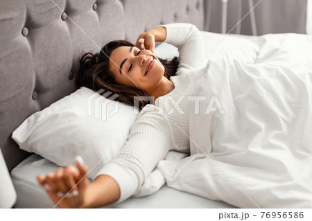Happy young African American woman stretching after waking up Happy young African American woman stretching after waking up 76956586