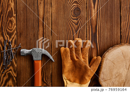 Screw nails, hammer and glove on wooden background Screw nails, hammer and glove on wooden background 76959164
