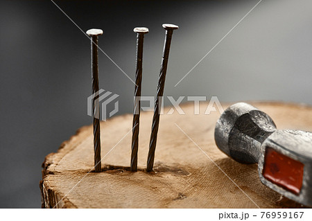 Screw nails and hammer on stump, grey background Screw nails and hammer on stump, grey background 76959167