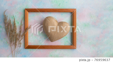 A frame with a heart in the papier mache technique and Pampas dry grass on a delicate background . Valentine's Day concept, greeting card, banner for the holiday. 76959637