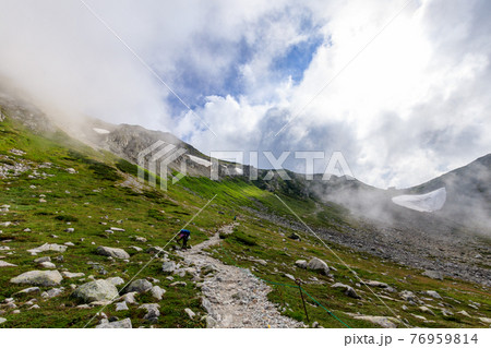 雲に覆われた幻想的な剱沢雪渓と登山者 76959814