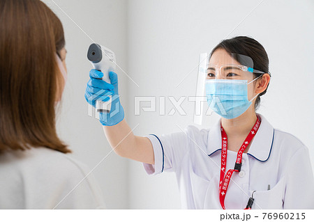 非接触体温計で体温測定をする看護師 76960215