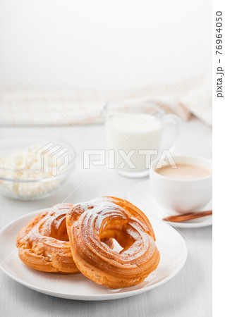 Morning coffee with cake. Custard rings, coffee, cream, cottage cheese on a white wooden table. Vertical image Morning coffee with cake. Custard rings, coffee, cream, cottage cheese on a white wooden table. Vertical image 76964050