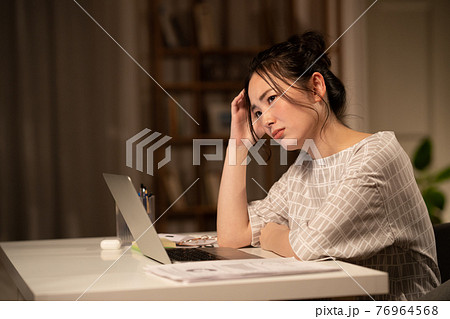 テレワークの残業で疲れる若い女性の写真素材