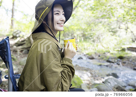 アウトドアチェアに座って飲み物を飲む女性　トレッキングイメージ 76966056