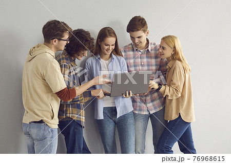 Happy teen girl showing laptop to smiling teenager friends studio portrait 76968615