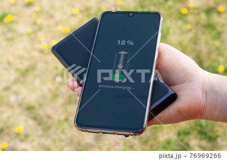 Smartphone charging without cable from induction power bank in the woman hand. Modern technology concept. 76969266