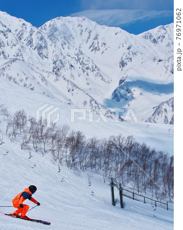 白馬八方尾根スキー場　白馬三山を背景に黒菱ゲレンデを滑るスキーヤー 76971062