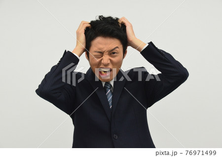頭をかきむしる若い男性 76971499