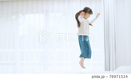 室内でジャンプする女の子 76971524