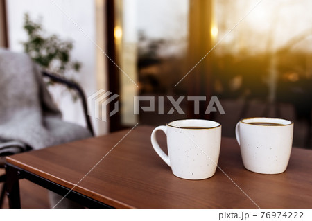 Two cups of coffee on the table on the wooden brown terrace Two cups of coffee on the table on the wooden brown terrace 76974222
