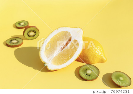 Halves of lemon with shadow, sliced kiwi cuts on yellow background Halves of lemon with shadow, sliced kiwi cuts on yellow background 76974251