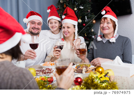 Family at dining table for Christmas dinner Family at dining table for Christmas dinner 76974975