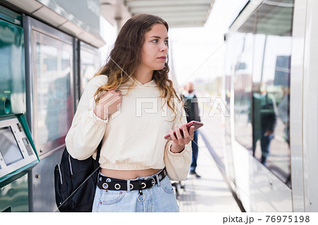 Woman waiting for tram on platform of public transport station Woman waiting for tram on platform of public transport station 76975198