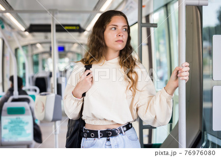 Young positive woman traveling in tram 76976080