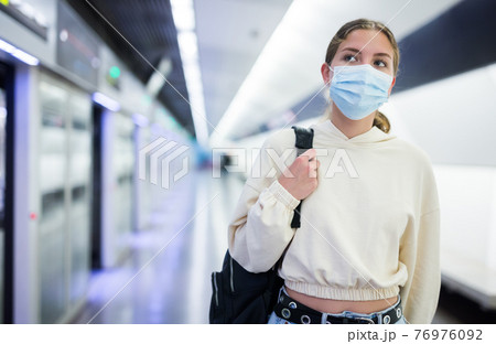 Young woman in face mask waiting for train Young woman in face mask waiting for train 76976092