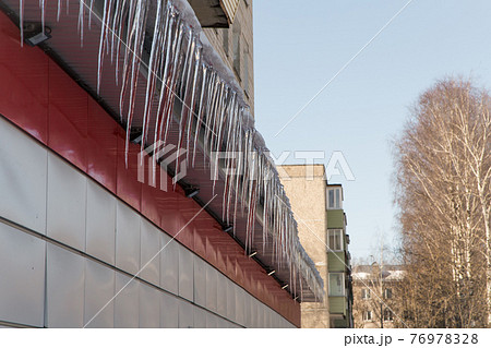 Long icicles hang from the roof of a store in the city. Long icicles hang from the roof of a store in the city. 76978328