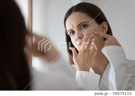 Stressed frowning teenage girl focused on beauty care problem Stressed frowning teenage girl focused on beauty care problem 76979153