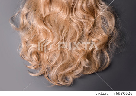 Blonde hair texture. Wavy long curly blond hair close up as background. Hair extensions, materials and cosmetics, wig, hair care. Hairstyle, haircut or dying in salon. 76980626