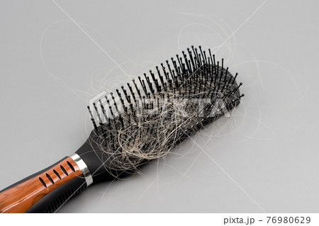 Hair loss problem, hairbrush with a lot of fallen hairs on grey background. Bunch of blonde hair on the comb. Losing too much hair. Healthcare concept. 76980629