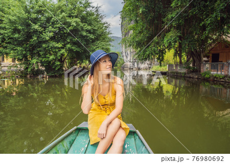Woman tourist in boat on the lake Tam Coc, Ninh Binh, Viet nam. It's is UNESCO World Heritage Site, renowned for its boat cave tours. It's Halong Bay on land of Vietnam. Vietnam reopens borders after Woman tourist in boat on the lake Tam Coc, Ninh Binh, Viet nam. It's is UNESCO World Heritage Site, renowned for its boat cave tours. It's Halong Bay on land of Vietnam. Vietnam reopens borders after 76980692