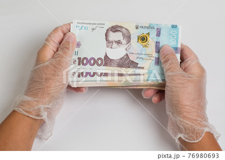 Stack of ukrainian hryvnia banknotes in gloved hands 76980693