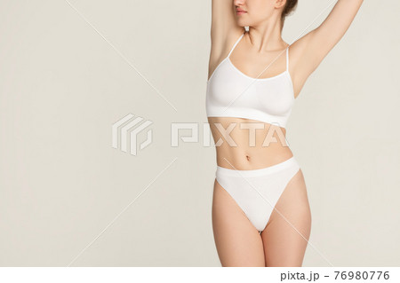 Cropped slim tanned beautiful woman in underwear isolated over gray background. 76980776
