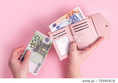 Hands holding wallet, counting cash or paying. Pink leather wallet with euro money in female hands. Woman's hands taking European bank notes out of purse. Money, finances, shopping. Free copy space. 76980828