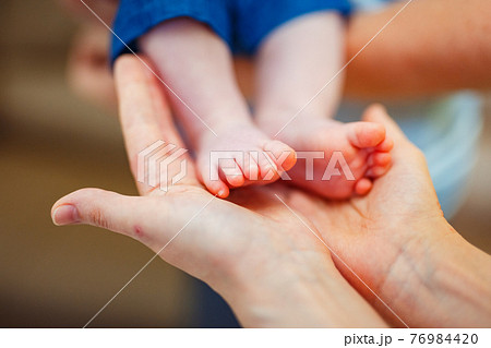 Baby foot in mother hands. Baby foot in mother hands. 76984420