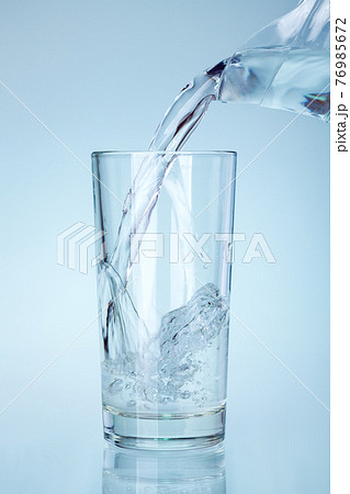 the clear glass is filled with water from the spout of the glass jug a stream of water with splashes and bubbles saturates and humidifies, nobody. 76985672