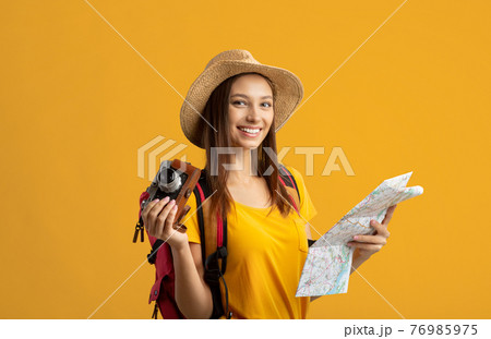 Happy young woman backpacker holding city map and camera 76985975