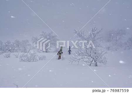 荒れ狂う雪山に入山するスノーボーダー 荒れ狂う雪山に入山するスノーボーダー 76987559