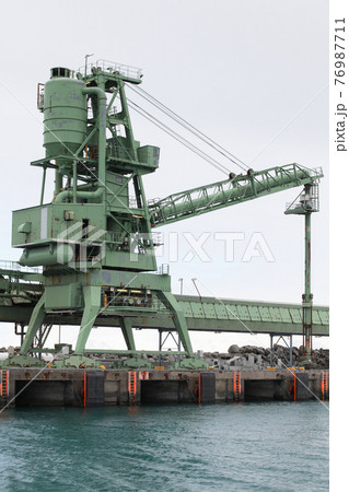 Green bulker crane is near transporter 76987711