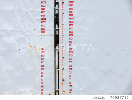Tide gauge marking is on gray dry dock hull 76987712