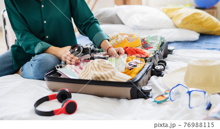 Unrecognizable woman with suitcase packing for holiday at home, coronavirus concept. 76988115