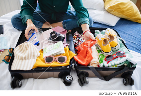 Unrecognizable woman with suitcase packing for holiday at home, coronavirus concept. 76988116