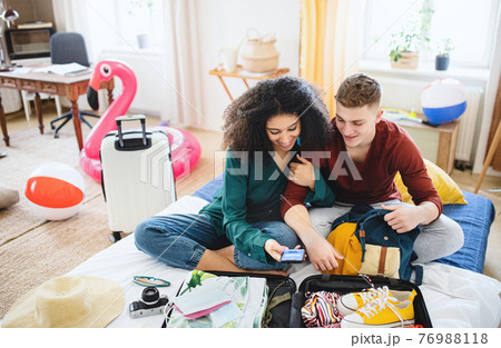 Young couple with laptop packing for summer holiday, coronavirus concept. 76988118