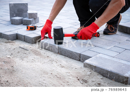 The master in yellow gloves lays paving stones 76989643