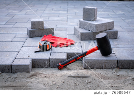 The master in yellow gloves lays paving stones The master in yellow gloves lays paving stones 76989647